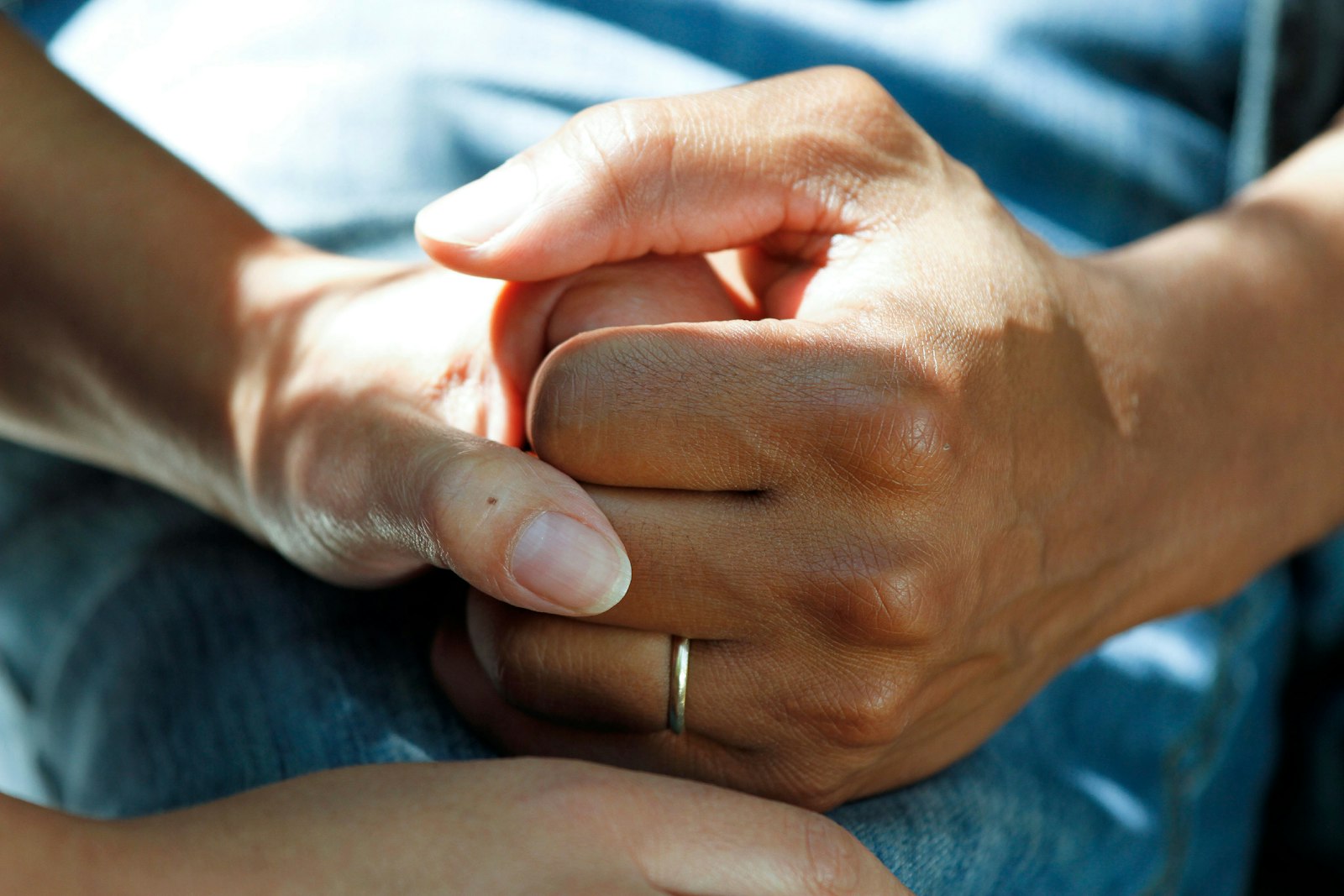 One person's hands holding another's in a gesture of care and reassurance