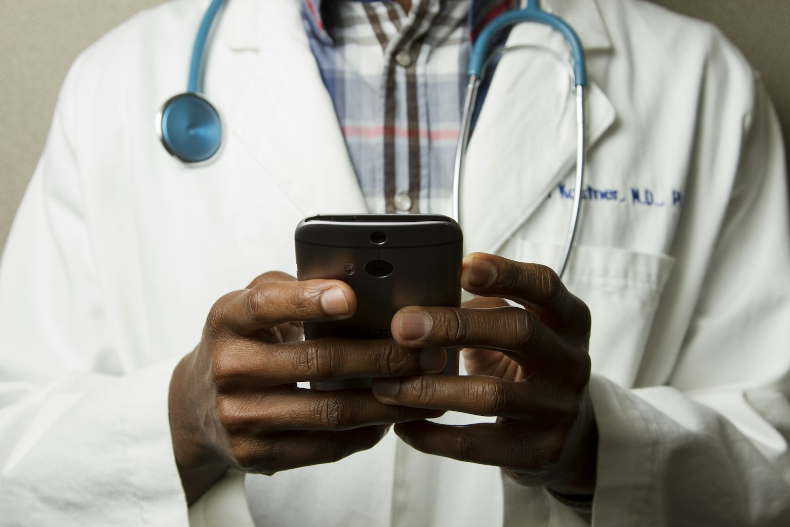 Close view of a healthcare professional in a white coat holding a phone