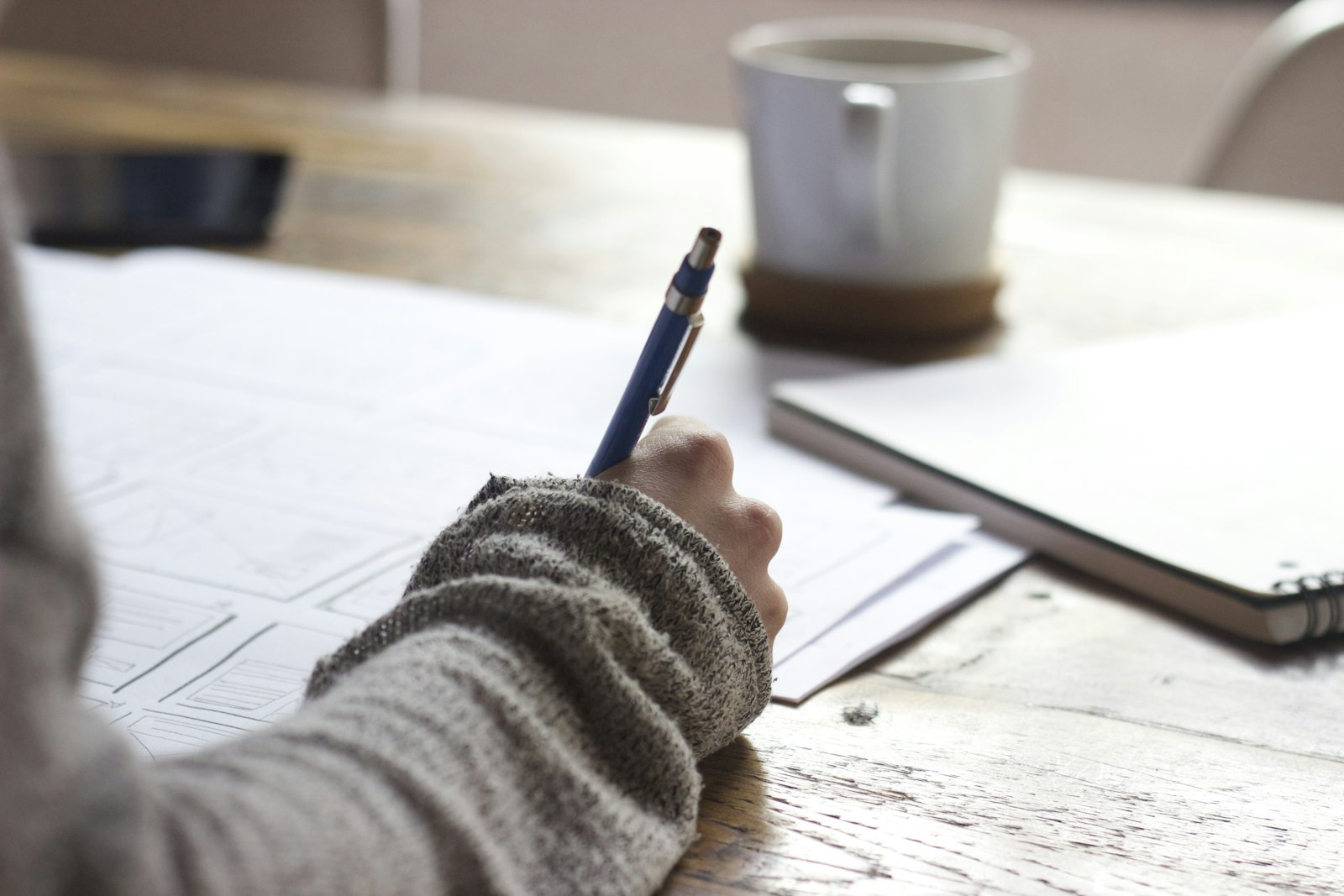 Close-up of a hand writing notes in a notebook